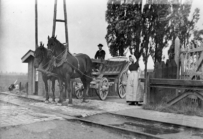 167608 Afbeelding van een paard en wagen met twee personen in Zeeuwse klederdracht bij een spoorwegovergang bij Goes.